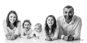 photos sur fond blanc d'une famille allongée sur le sol avec des grands sourires